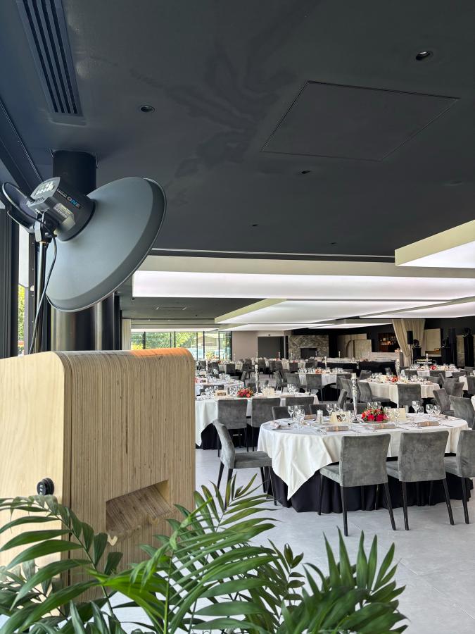 De gelaagde houten zijkant van de booth, met daarachter een zaal vol gedekte ronde tafels