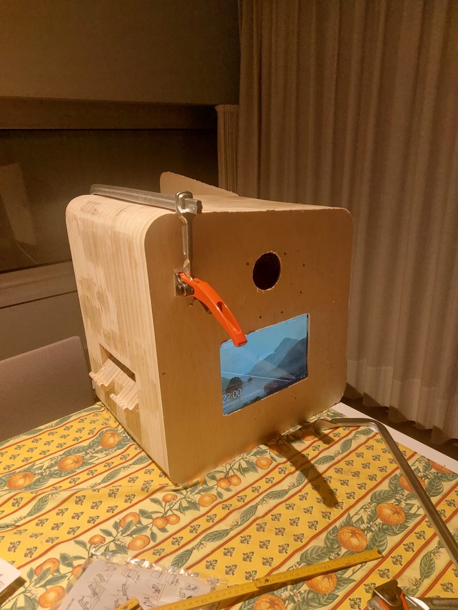 De ruwe houten booth in aanbouw, met een lijmklem eraan, op een tafel